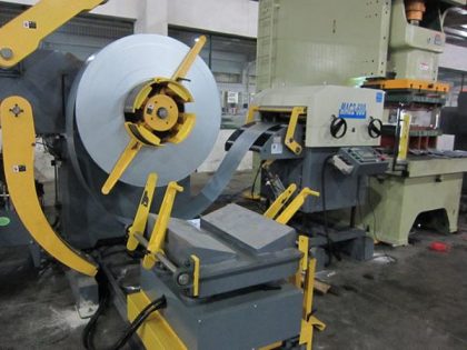 Leveling machine with metal strip material being fed into stamping press